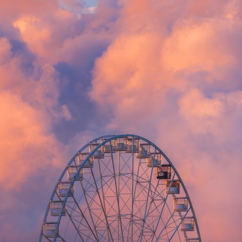Diabelskie koło działające na terenie Holiday Park w Szczecinie na tle pięknych chmur o wschodzie słońca.