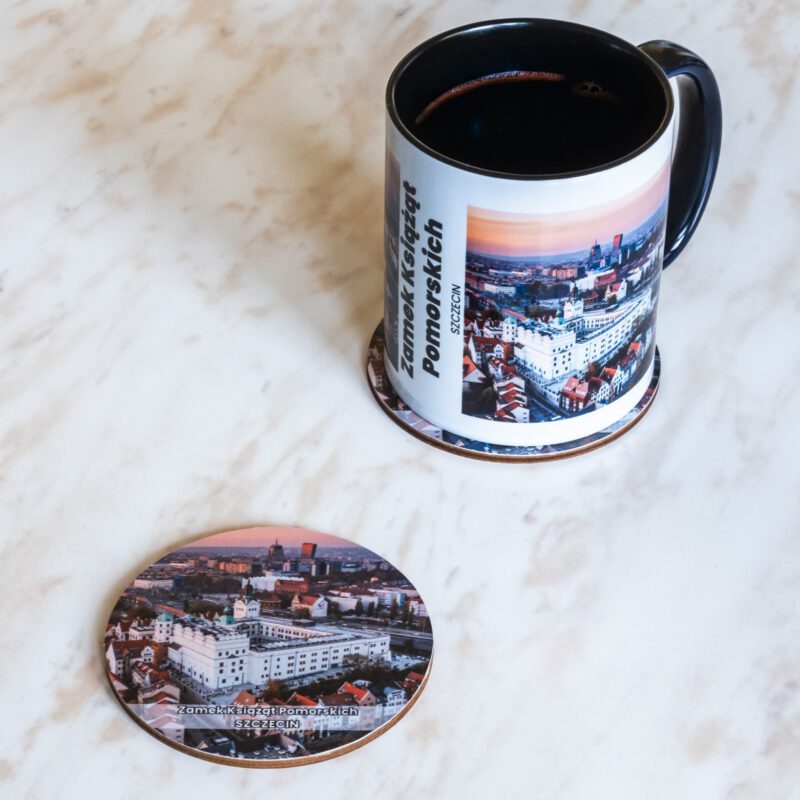Ceramiczny kubek i drewniana podkładka z motywem Zamku Książąt Pomorskich w Szczecinie.